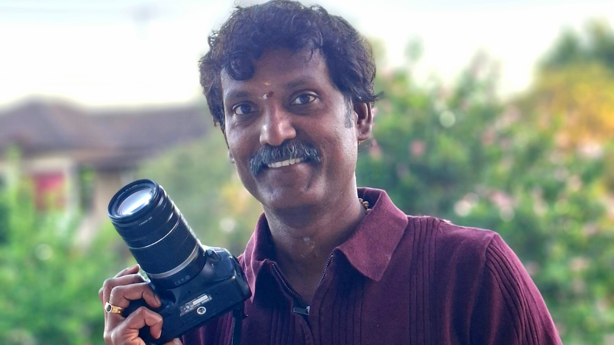 A photographs of Jai holding his DSLR camera.